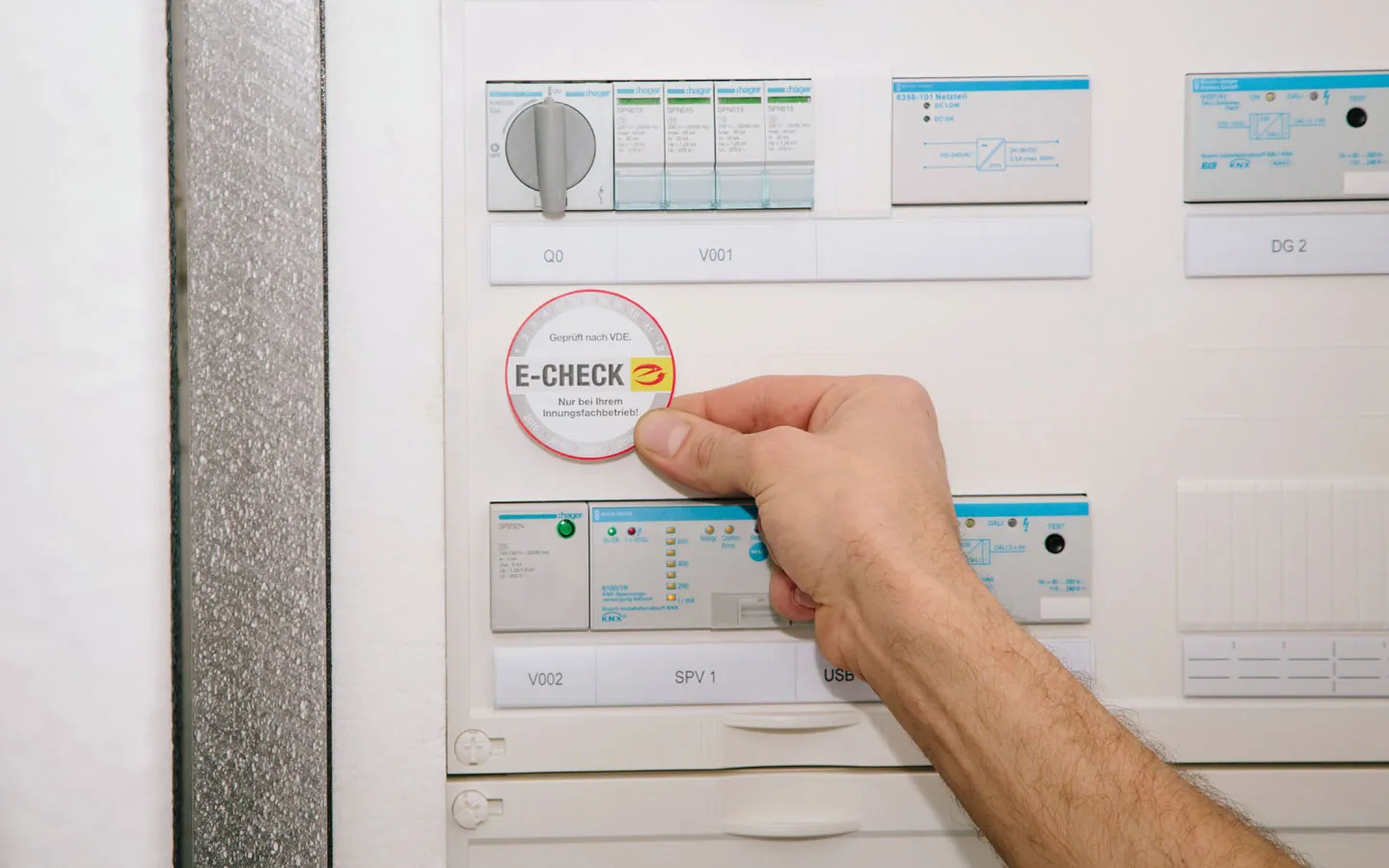 E-CHECK - Mitarbeiter klebt in der Verteilung die E-CHECK Plakette an · Elektro Dörr