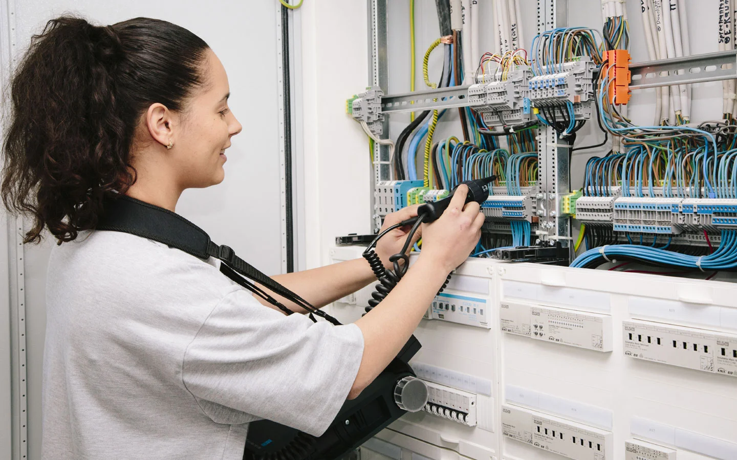 E-CHECK - Mitarbeiterin prüft im Schaltschrank mit einem Meßgerät · Elektro Dörr